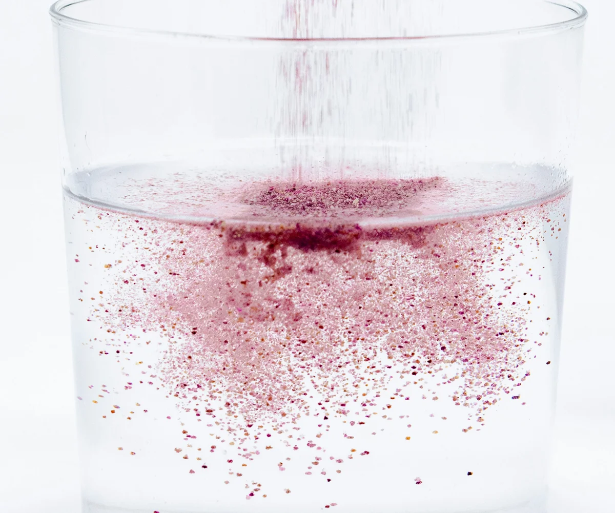 Polvere rossastra versata in un bicchiere trasparente – integratori alimentari